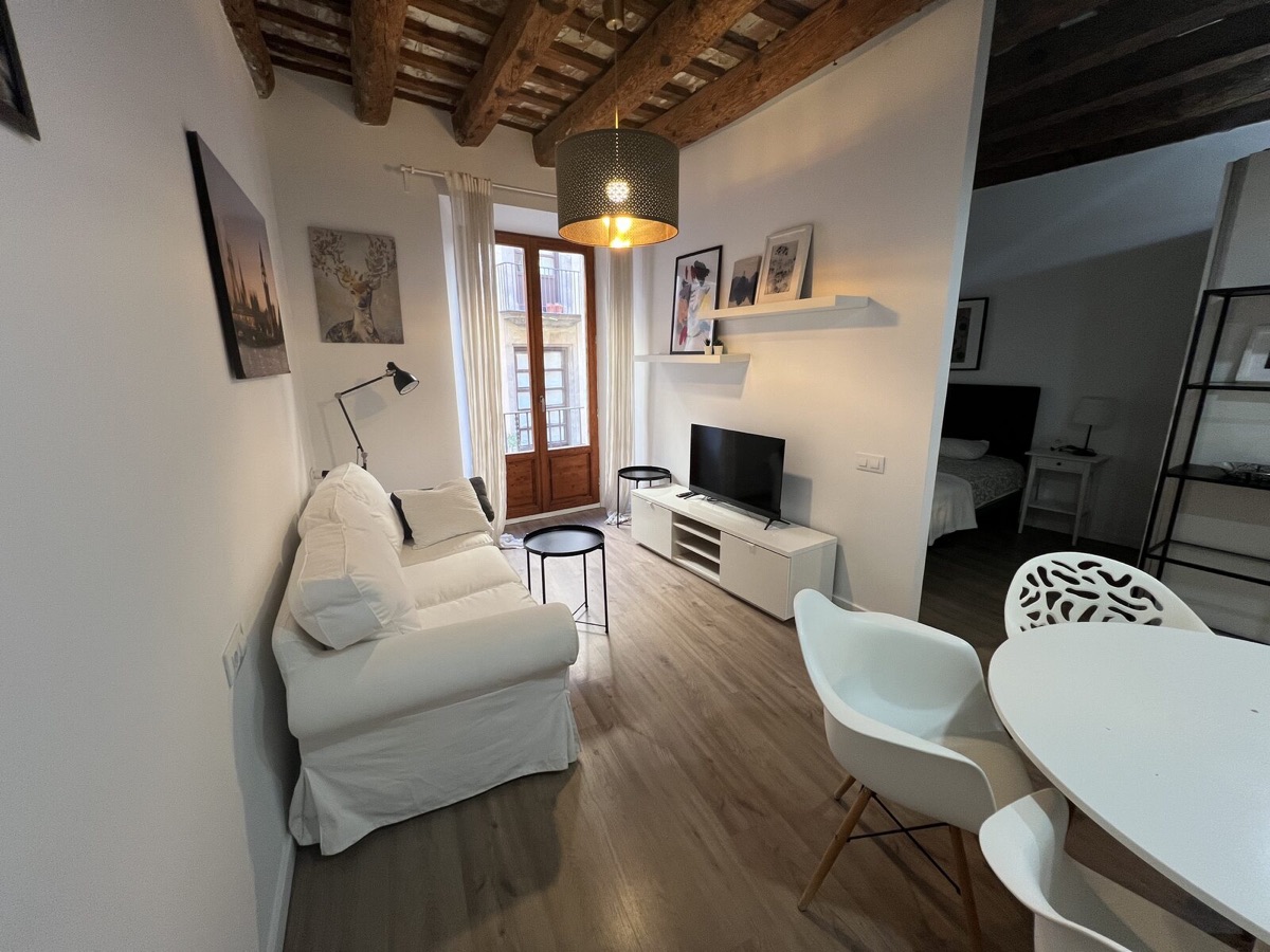 Living room with exposed wooden beams and a wood-framed balcony door