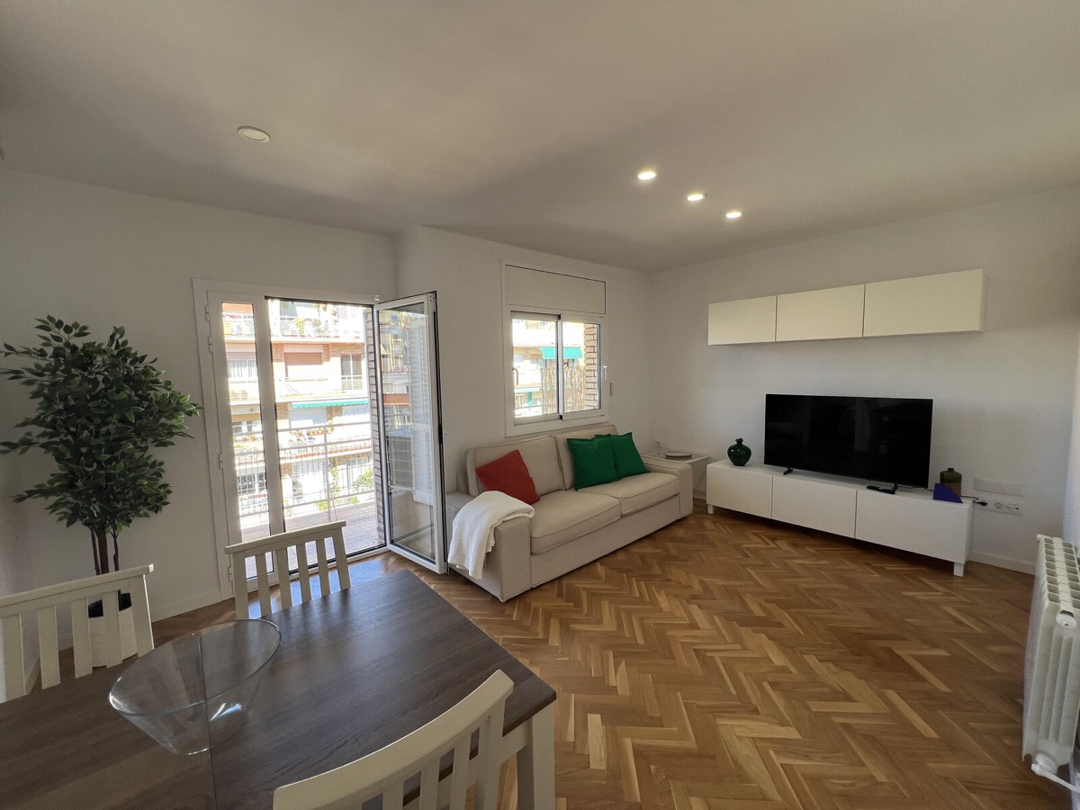 Living room with herringbone floor, sofa and a sunny balcony