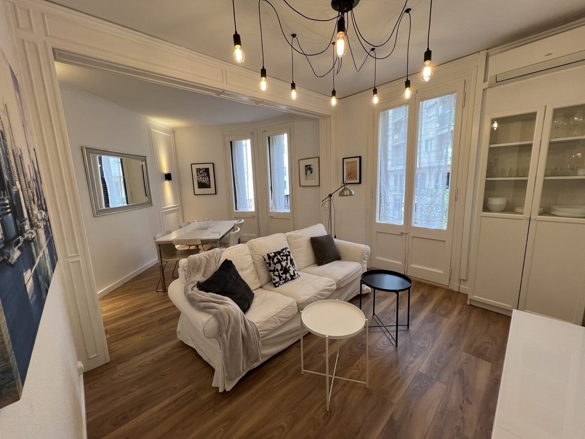 Living room with ceiling mouldings, a pendant-bulb light and balconies onto the street